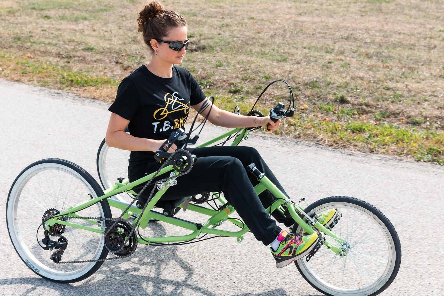 Ragazza in sella a T.B. Bike verde, con le gambe sullo sterzo