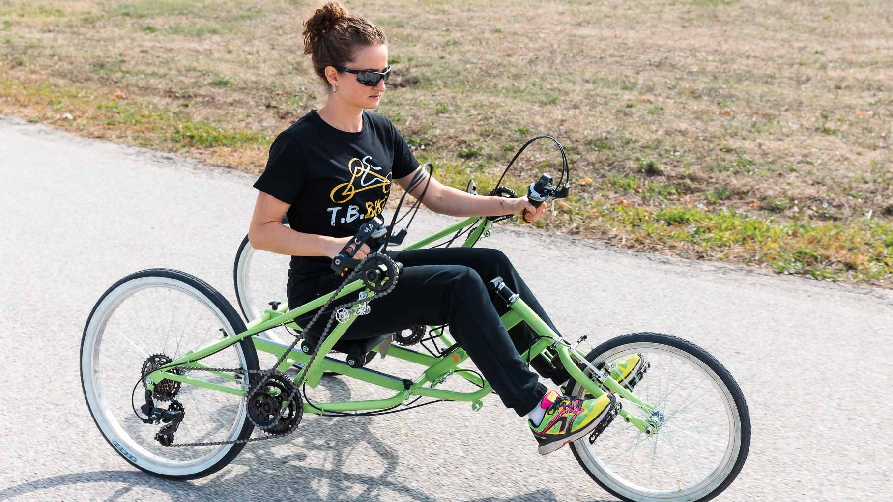 Ragazza in sella a T.B. Bike verde, con le gambe sullo sterzo