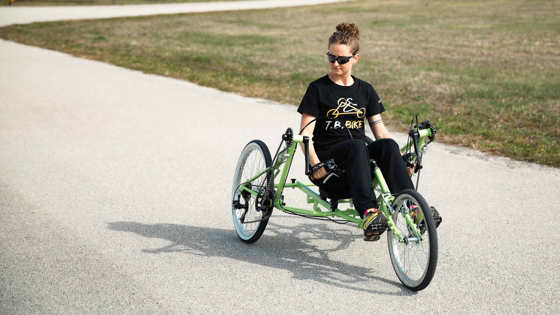 Ragazza seduta su T.B. Bike verde lungo una pista ciclabile