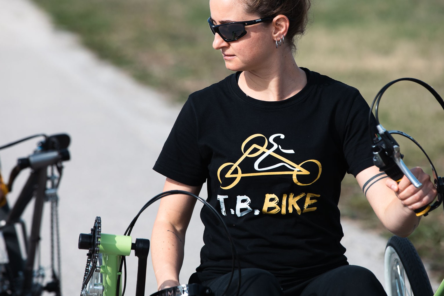 Ragazza con la maglia T.B. Bike tiene il manubrio della bici verde